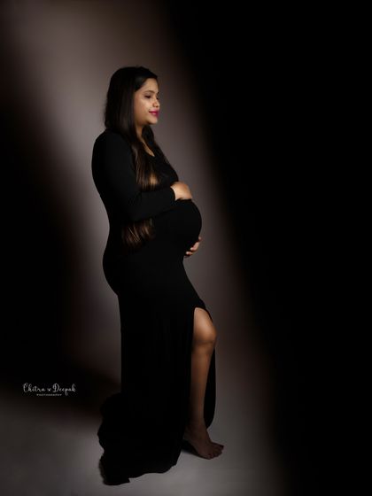 Simple, classic, and elegant. A black dress with a side slit is a timeless choice for a maternity shoot, focusing on the beautiful silhouette.