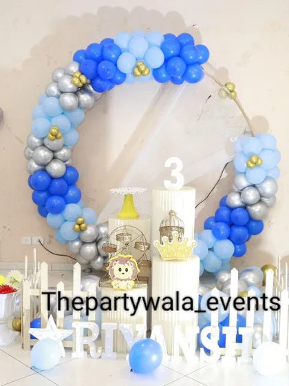 A wider view of the blue and silver balloon ring, showing the full setup with the picket fence and props.