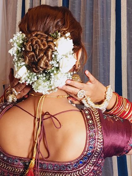 A close-up of this intricate rose bun, showing how the curls are pinned to mimic the shape of a flower. It's a unique and artistic take on a classic bridal updo.