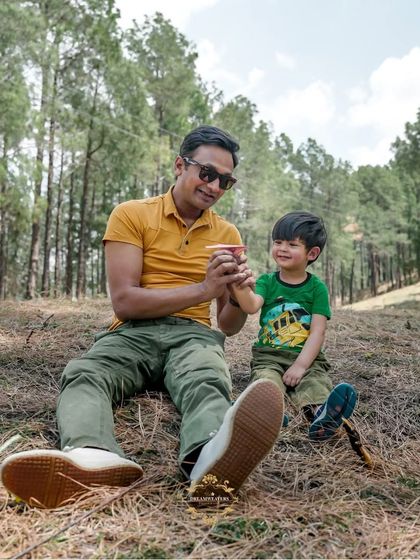 A father and son enjoying a playful moment together in a beautiful, wooded area.