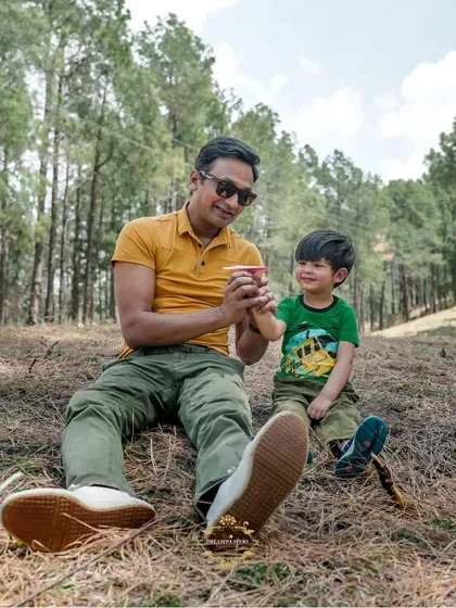 A father and son enjoying a playful moment together in a beautiful, wooded area.