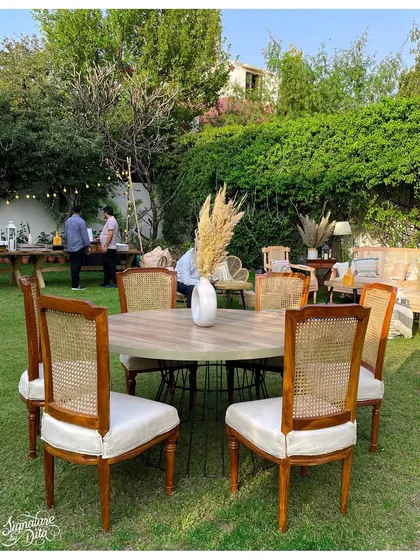 Guest seating was arranged to encourage conversation, with round tables and classic cane-back chairs creating an elegant dining setup on the lawn.