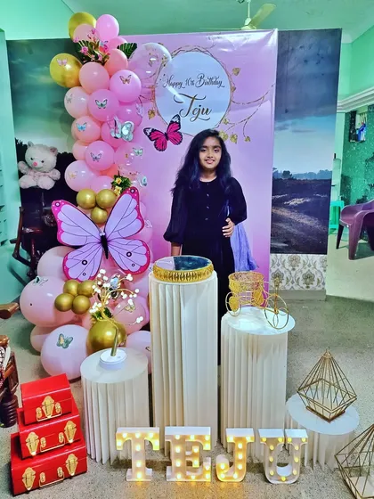 A sweet 16th birthday celebration with a pink and gold butterfly theme. The setup includes a personalized backdrop and marquee letters.