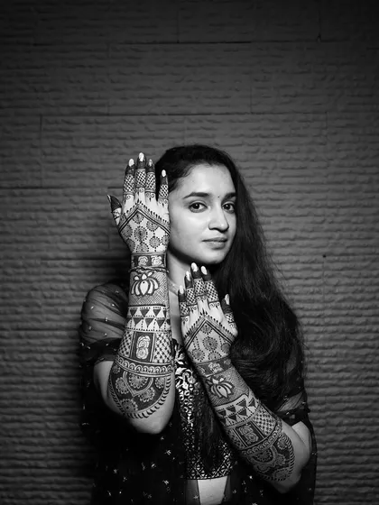 A beautiful black and white portrait of the bride, her hands framing her face to showcase the stunning henna art.
