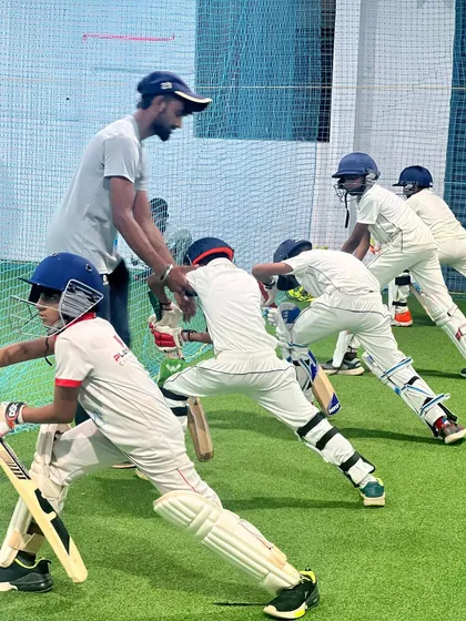 Teamwork and fundamentals are at the heart of my coaching. Here, a group of young players works on their batting stance in our spacious indoor facility, ensuring they learn and grow together.