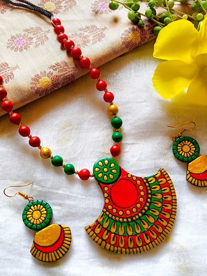 A beautiful fan-shaped pendant necklace in a festive red, green, and gold combination.