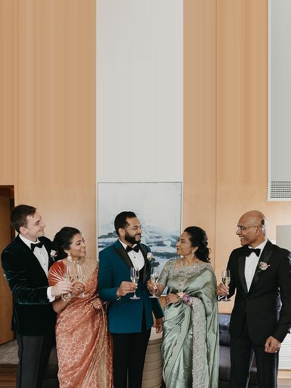 A candid moment of celebration with champagne. This image shows the easy elegance of the family's coordinated attire. The mix of teal, sage green, rose gold, and black creates a visually rich and harmonious palette that looks stunning both in formal portraits and in relaxed, happy moments.
