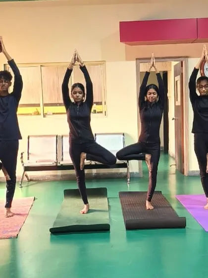 Athletes holding the Vrikshasana (tree pose) during a yoga session. This pose is excellent for improving balance and concentration, two of the most critical skills for a shooter.