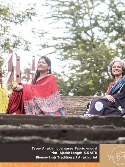 A different angle of our two customers enjoying their Ajrakh sarees. The natural setting perfectly complements the earthy tones and traditional prints of the fabric.