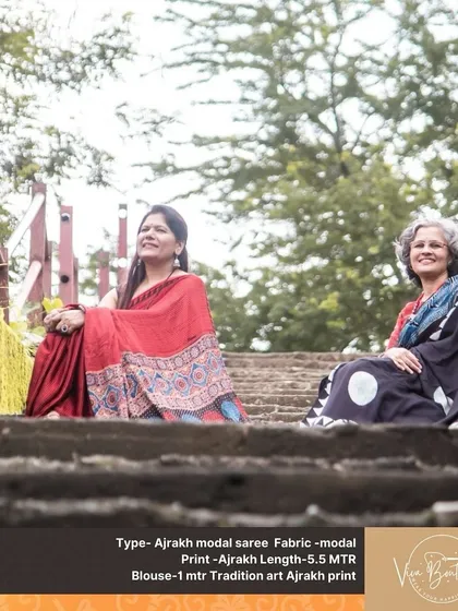 A different angle of our two customers enjoying their Ajrakh sarees. The natural setting perfectly complements the earthy tones and traditional prints of the fabric.