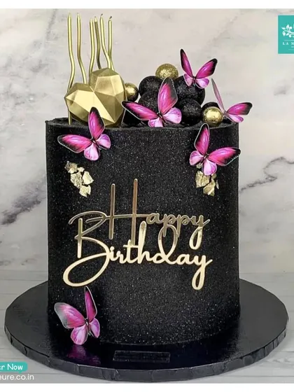 Let's create something bold and glamorous for your birthday. This striking custom cake is covered in black glitter and decorated with vibrant magenta butterflies, gold accents, and a stylish 'Happy Birthday' acrylic topper.