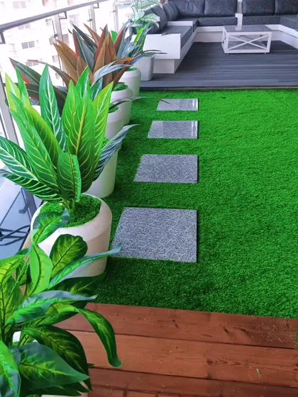 A close-up of a balcony makeover in Rajkot. We used a combination of artificial grass and a wooden deck, with stepping stones and beautiful planters.