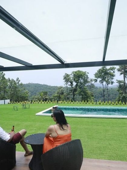 A couple enjoying the view from their private patio at Panorama Peaks, Coorg, overlooking the lawn and pool area.