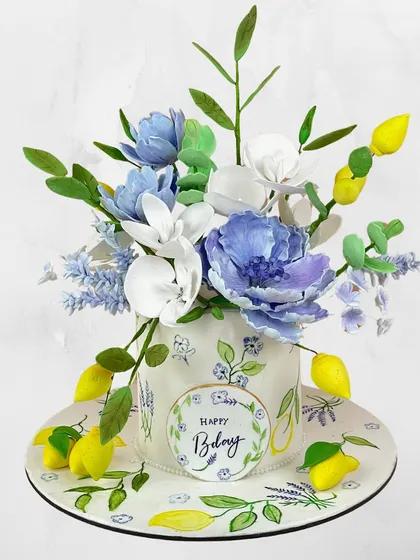 A birthday cake that feels like a bouquet from a French garden. This hand-painted cake is topped with sugar flowers and lemons for a fresh, artistic look.