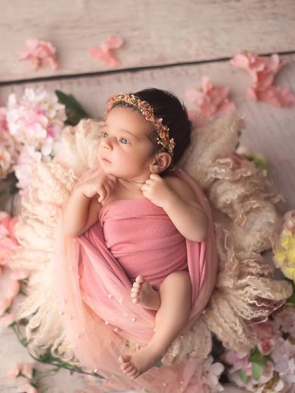A beautiful portrait of an awake baby girl in a nest of pink flowers. Her curious gaze adds so much personality to this floral setup.