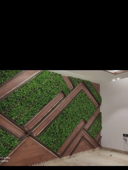 An indoor feature wall with a geometric pattern. I used dark wood framing to create angular sections, which are then filled with dense artificial greenery for a modern, textured look.