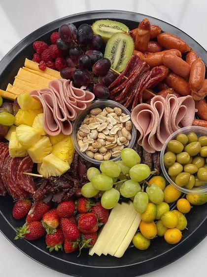 Our charcuterie and fruit platters are perfect for grazing. This board is generously filled with assorted cheeses, cured meats, sausages, nuts, olives, and a variety of fresh fruits like grapes, strawberries, and pineapple.