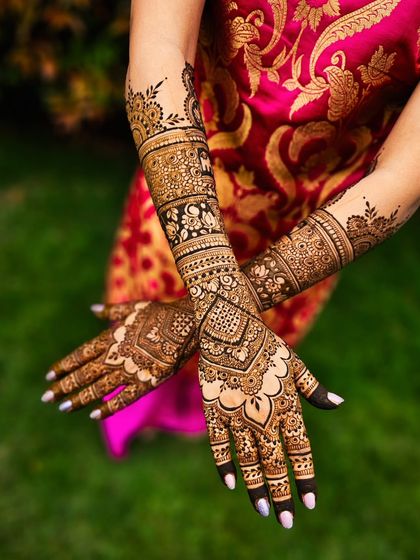 This bridal henna showcases a beautiful mix of checkerboard patterns, floral bands, and delicate scalloped edges for a complete and elegant look.