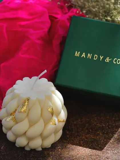 A luxury braided soy candle with gold foil accents, a festive and clean-burning decor piece.