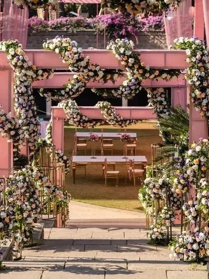 A stunning entrance for a wedding, with structures completely covered in intricate floral arrangements. This creates an incredibly lush and high-end feel.