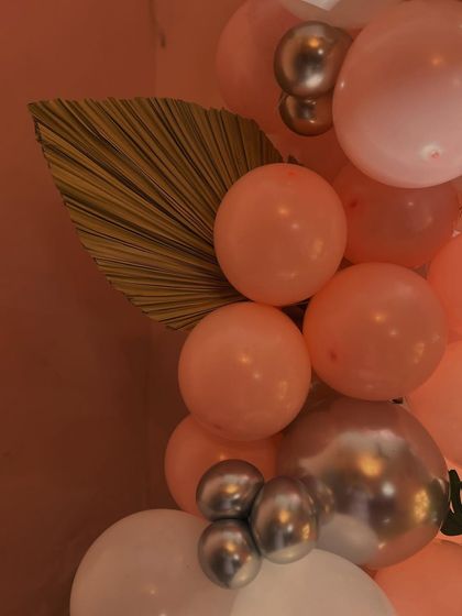 A detail shot of the balloon garland, showing the mix of pastel pink and metallic balloons with a touch of greenery.