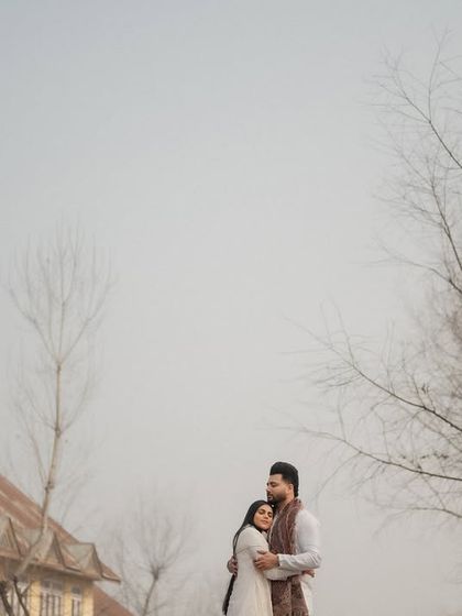 An embrace against the rustic backdrop of a Kashmiri village. We love exploring offbeat locations to create authentic and memorable pre-wedding portraits that reflect the local culture.