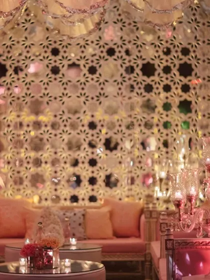 Another angle of the Sheesh Mahal lounge, showing how the intricate mirror-work walls and ceiling create a stunning, multi-faceted reflection of light. The pastel pink sofas add a touch of softness to the glittering setup.
