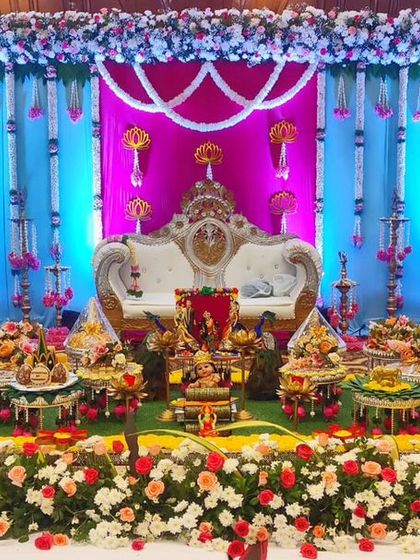 A colorful stage with a backdrop of hanging blue and pink floral garlands, creating a vibrant and festive look for a baby shower.