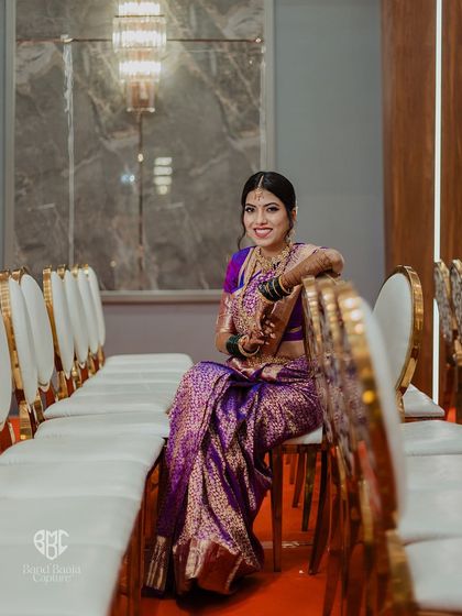 A graceful portrait of the bride seated in her stunning purple saree, waiting for the ceremony to begin.