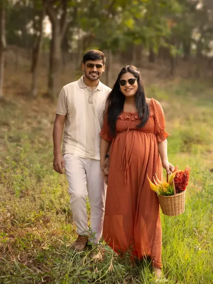 A happy stroll through the woods. This couple's portrait captures a candid, joyful moment, with the mother-to-be carrying a basket of flowers, adding a rustic touch.