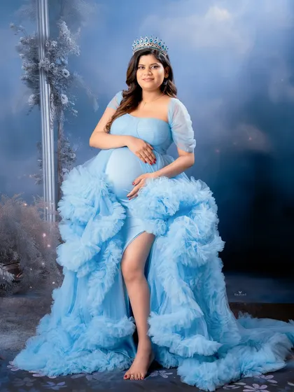 A fairytale moment captured in our studio. This mom-to-be looks like a queen in a ruffled light blue gown, complete with a tiara and a dreamy, cloud-like background.