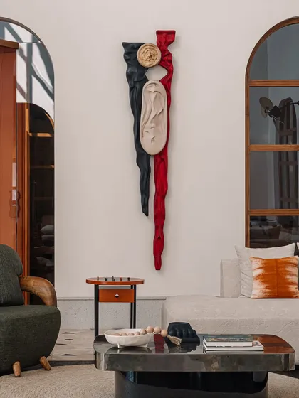 The 'Squal Man' wall sculpture, carved in ash wood with dramatic red and black stains, adds a powerful narrative element to this living room. It's a testament to our belief in collaborating with artists to create pieces with deep stories.