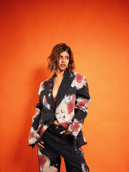 A bold and energetic studio shot for Sejal Kumar's collaboration with Apple. The vibrant orange backdrop and dynamic pose create a high-impact image that feels modern and confident, perfect for a digital campaign.