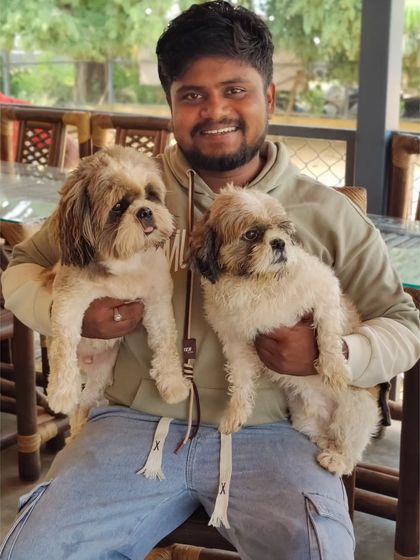 A visitor with a lap full of love, holding two adorable Shih Tzus at once.