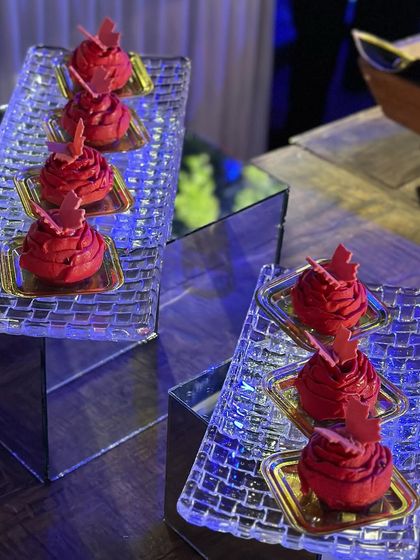 Vibrant red desserts on a mirrored display. The striking colour and elegant presentation make these bite-sized treats a standout feature of our dessert buffet.