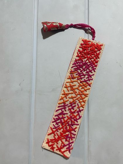 A vibrant bookmark made with a freestyle cross-stitch pattern. The mix of warm colors creates a beautiful, abstract design.