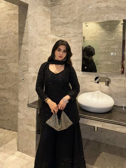 A full-length view of the black sequin suit, complete with a matching clutch.