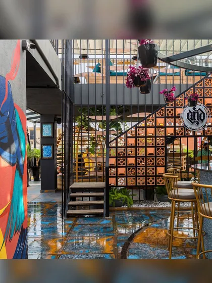The completed bar area, where industrial metalwork, earthy terracotta, and colorful art come together. The gold bar stools add a touch of glamour to the eclectic and textured space.