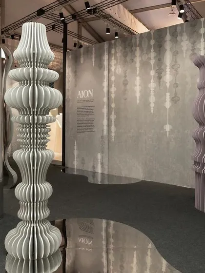 Another perspective of the 'Silver Escapade' installation. The repeating vertical lines of the paper totems and the reflective surfaces create a dynamic and visually complex space.