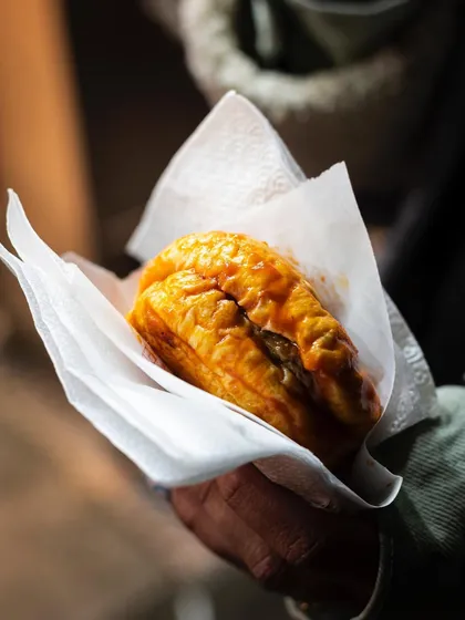 A "wet burger" (islak burger), a unique Istanbul street food. The shot highlights its saucy, unique texture.