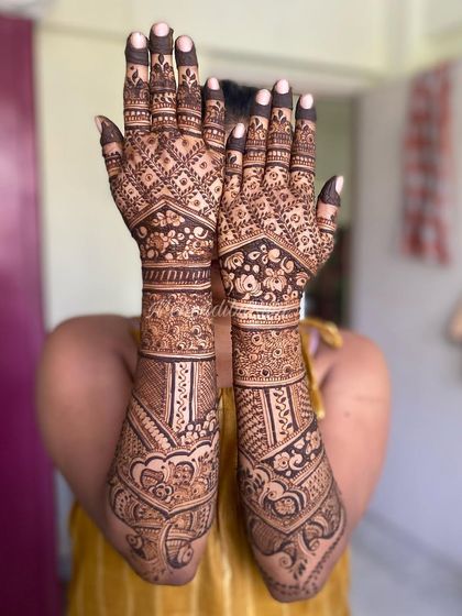 A full view of a bridal design held up to the camera. This shows the symmetry and complexity of the patterns, from the fingertips all the way up the forearms.