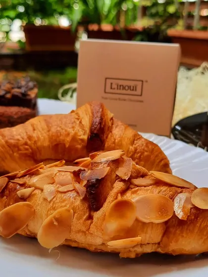 A beautiful spread of our treats, including almond croissants and pastries, enjoyed in a garden setting. This is the experience we hope to provide, a taste of luxury made right here in namma Bengaluru.