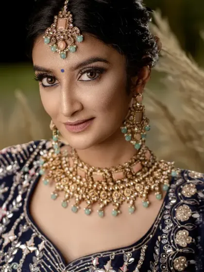 A stunning close-up of the bride against a backdrop of pampas grass. The golden hour lighting makes her glow, highlighting her intricate jewelry.