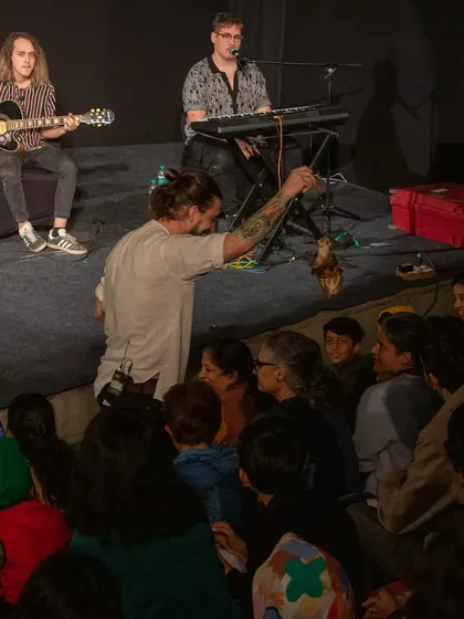 A puppeteer from Hungary's 'Dragon and the Devil' interacts with the audience, bringing a small bat-like marionette up close for everyone to see.
