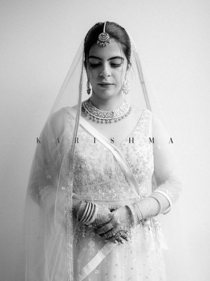 A serene and elegant black and white bridal portrait. Karishma's calm demeanor and the delicate details of her lehenga are beautifully rendered in this timeless shot.