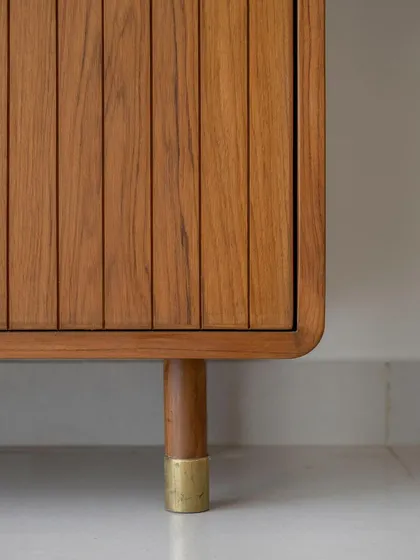 A detail of the 'Marshall' crockery unit's leg, showcasing the custom brass shoe that gives the collection its distinctive retro flair.