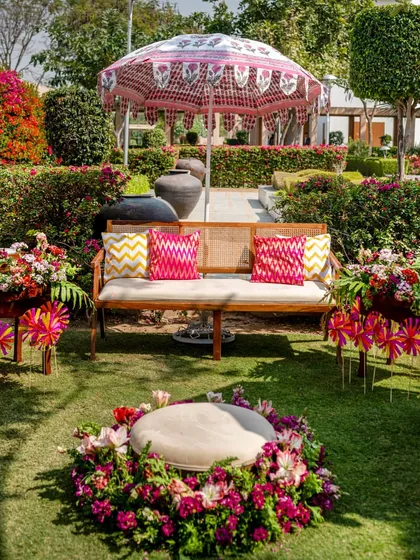 A beautiful seating area on the lawn, with a floral-ringed ottoman in the center, set against a backdrop of blooming bougainvillea.