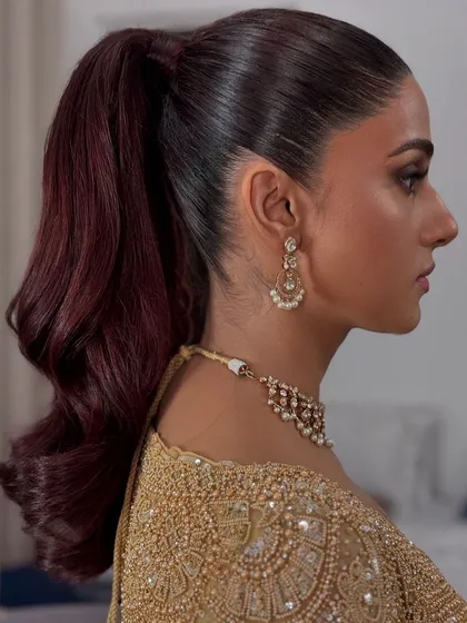 A sleek, high ponytail is a modern classic. This look combines a perfectly smooth base with voluminous, sculpted waves, a versatile style for both bridal and fashion events.