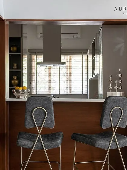 A pass-through bar area in a project by Aurora Studio, featuring our custom bar stools. The design, with its unique looped metal backrest, was chosen to provide comfort and style.
