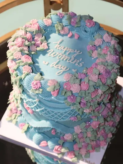 A top-down view of our Women's Day cake, highlighting the "Happy Women's Day" message surrounded by a wreath of buttercream roses.
